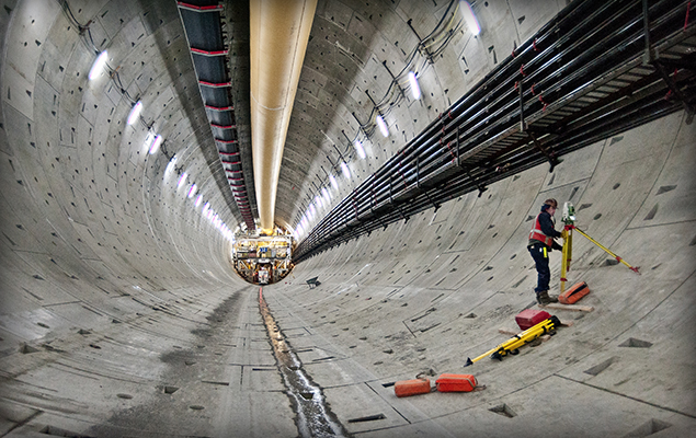 Surveyor in completed tunnel with Robbins boring machine in the distance